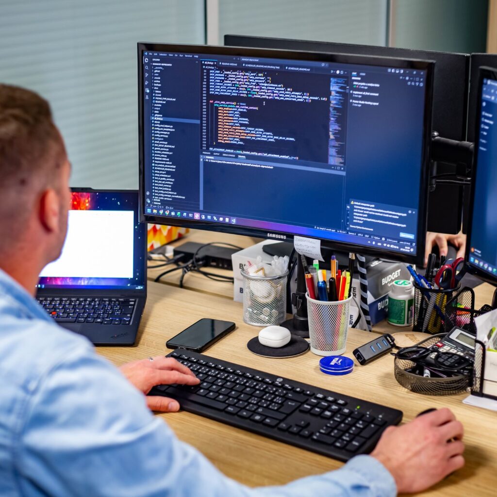 Člen týmu Sales House Group pracuje u počítače s daty a digitálními nástroji v kancelářském zázemí firmy.