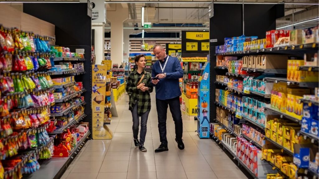 Členové týmu Sales House Group si pořizují společnou fotografii v prodejně a ukazují přátelskou atmosféru v oblasti merchandisingu a sales.