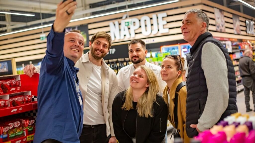Členové týmu Sales House Group procházejí prodejnou mezi regály a představují každodenní práci v merchandisingu a sales.