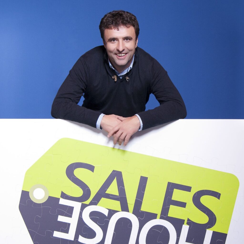 Archivní studiový snímek z roku 2013: usměvavý muž ze Sales House se opírá o panel s logem značky při zahájení nové éry společnosti.