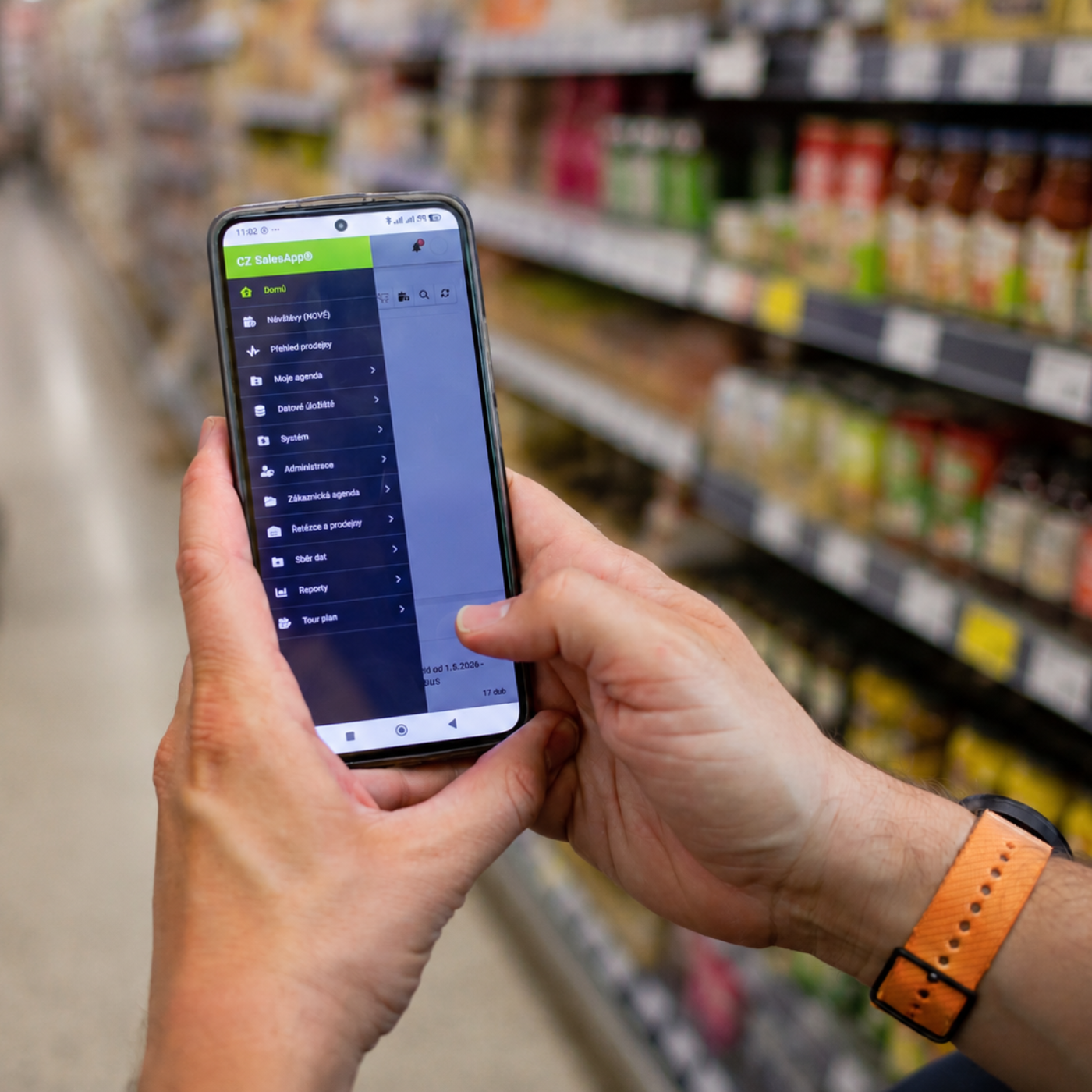 Merchandiser používá aplikaci SalesApp v prodejně při kontrole zboží v regálu.
